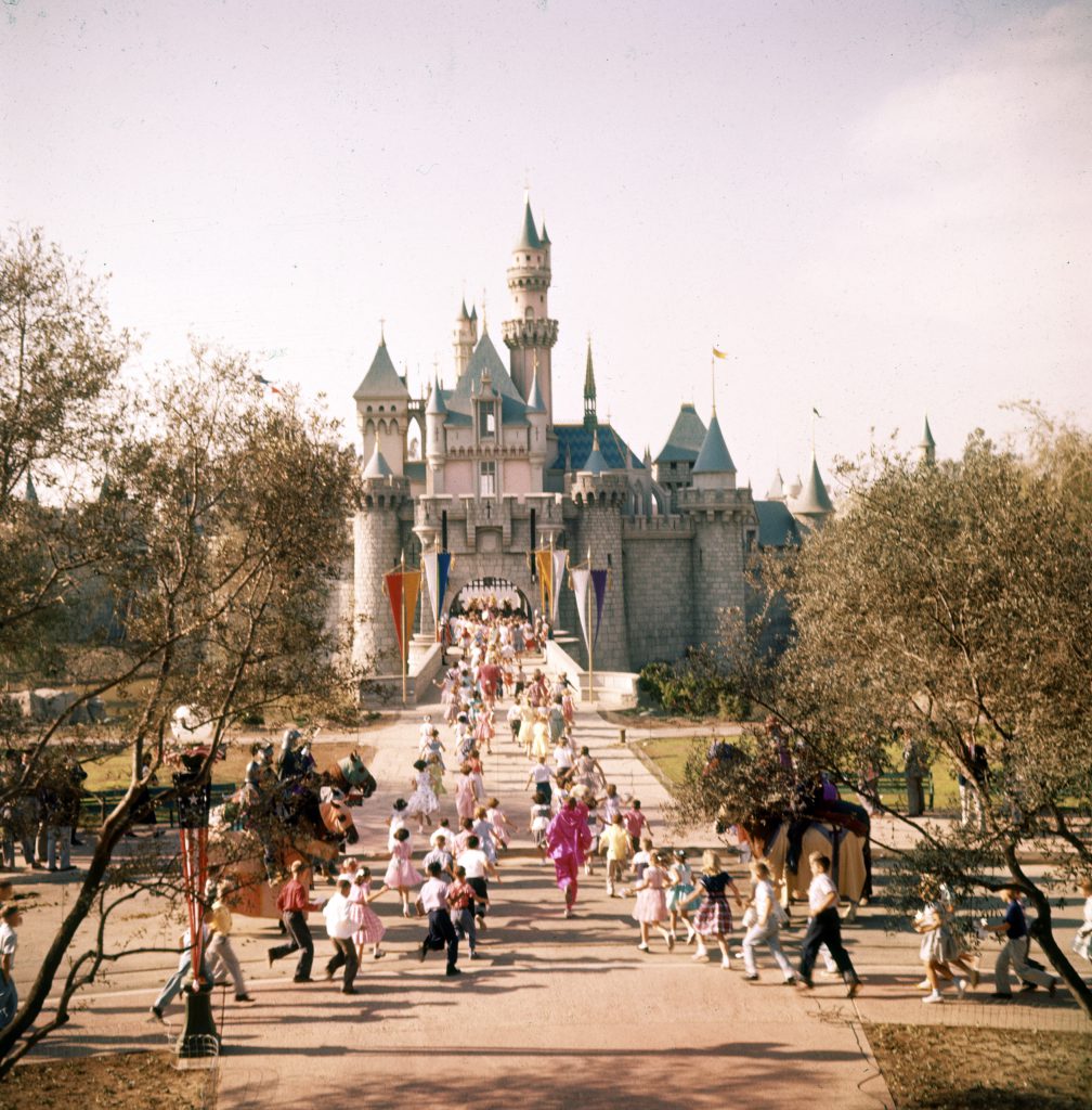 Sleeping Beauty's castle in Fantasyland is overrun by children crossing drawbridge over moat. Inside, Disney plnas a model torture chamber.